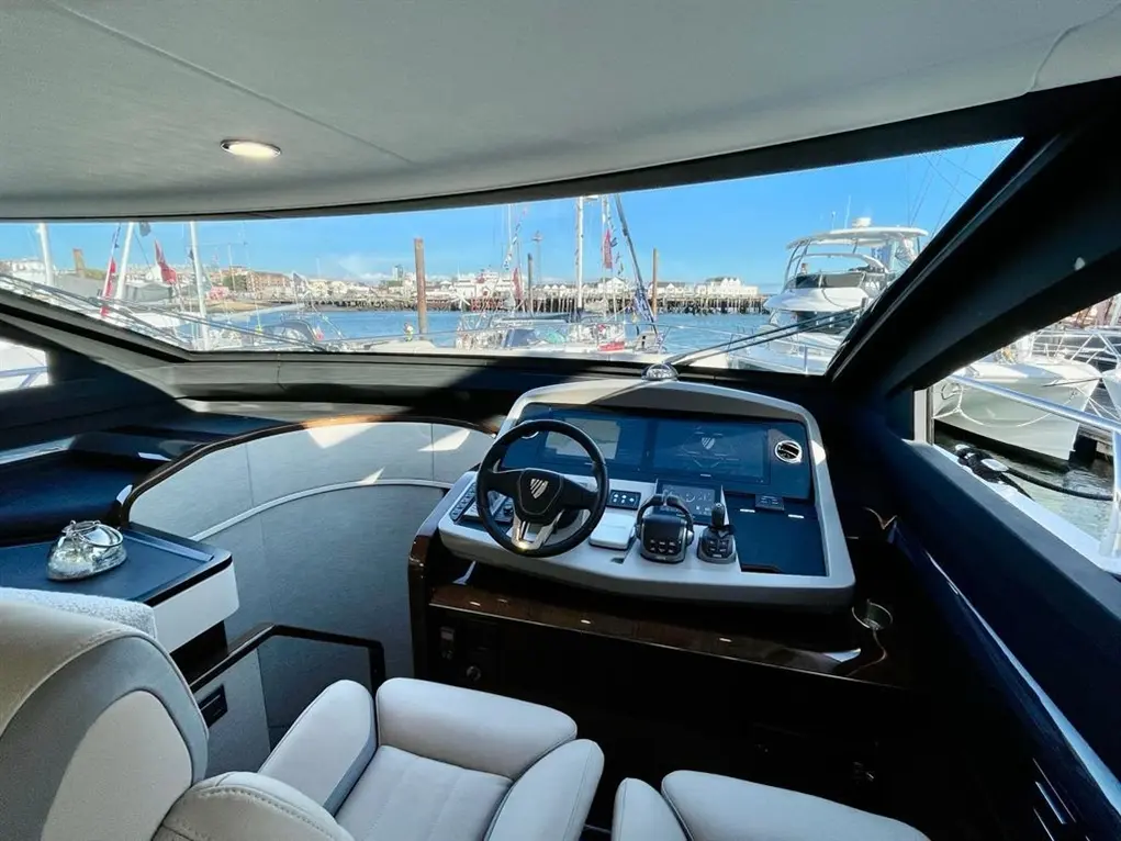 Luxury yacht interior showing the helm and marina view, featuring a steering wheel, control panel, and plush seating.